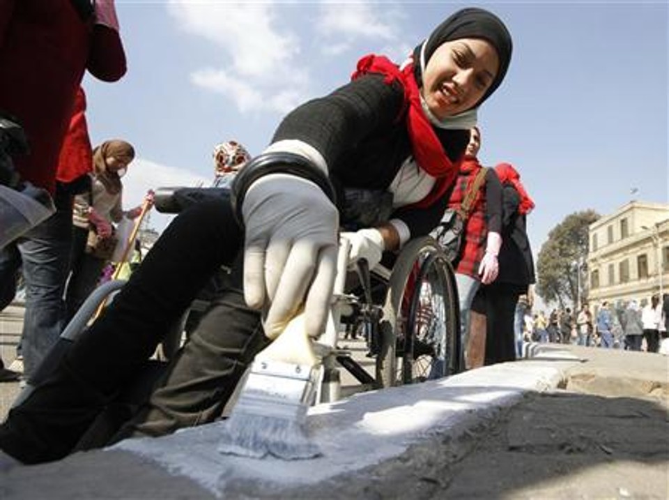 Mulher em cadeira de rodas pinta no chão da praça Tahrir, no Cairo | Reuters