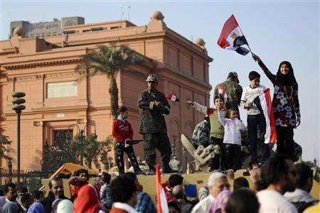 Jovens manifestantes agitam bandeiras em cima de tanque na Praça Tahrir, no Cairo | Reuters