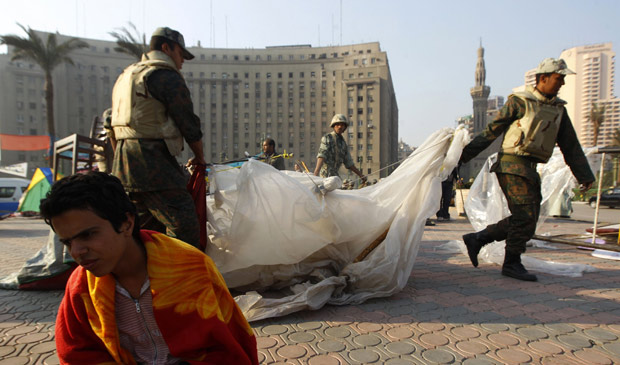 Manifestante antigoverno senta no chão da praça Tahrir, local símbolo dos protestos no Egito, enquanto militares removem barracas, neste domingo (13) | Reuters