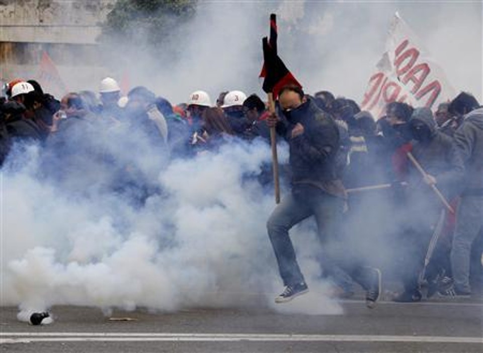 Manifestantes fogem de gás lacrimogêneo durante protestos em frente ao Parlamento, em Atenas, 23 de fevereiro de 2011 | REUTERS/Yiorgos Karahalis