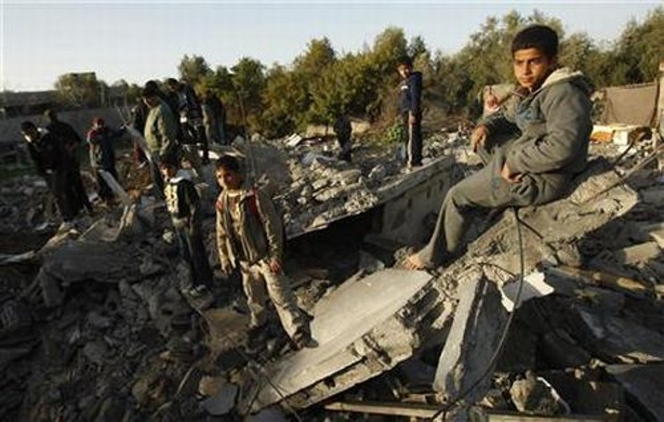 Garoto palestino sentado sobre os destroços de sua casa após ataque aéreo de Israel na Faixa de Gaza | Reuters
