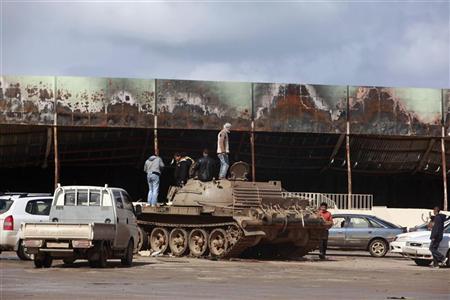 Manifestantes contrários ao governo sobem em tanque do Exército, em frente a uma base militar destruída em Benghazi | REUTERS/Asmaa Waguih