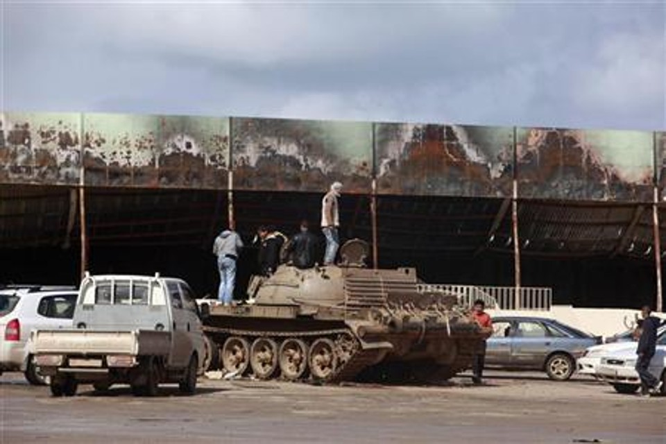 Manifestantes contrários ao governo sobem em tanque do Exército, em frente a uma base militar destruída em Benghazi | REUTERS/Asmaa Waguih