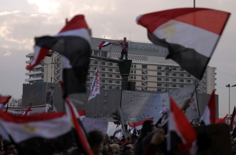 Opositores agitam bandeiras na praça Tahrir, no 13º dia de protestos em Cairo, capital egípcia | Patrick Baz / AFP Photo