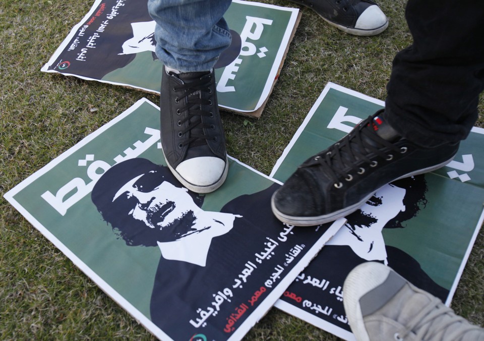 Protestantes pisam sobre cartazes com o rosto de Muamar Kadafi, durante ato em frente à sede da ONU, em Beirute | REUTERS/Sharif Karim