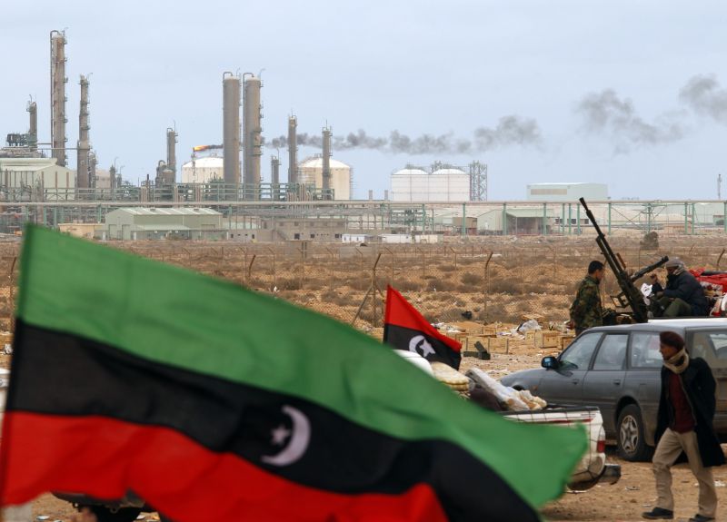 Rebeldes exibem bandeiras do Reino da Líbia em frente de refinaria de petróleo nas proximidades da cidade de Ras Lanuf, palco de violentos combates com as forças de Kadafi | Goran Tomasevic/Reuters