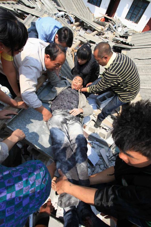 Voluntários ajudam a retirar um homem preso debaixo de escombros | AFP