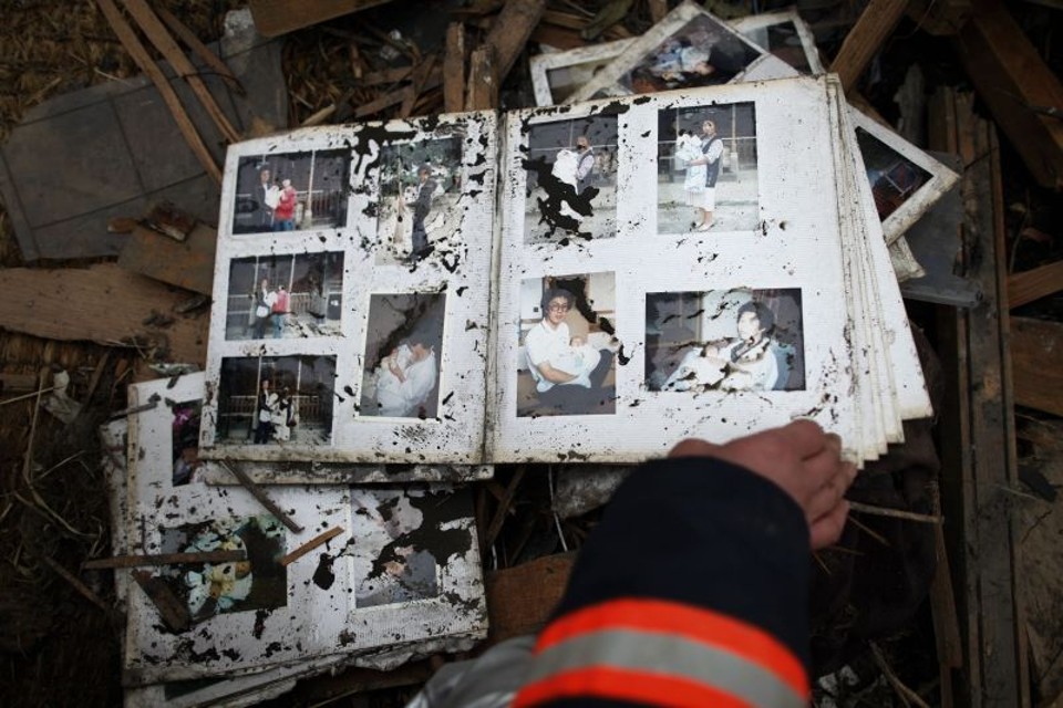 Bombeiro encontra um álbum de fotografias chamuscado dentro de uma casa destruída na pequena Otsuchi, cidade de 15 mil habitantes que pode ter perdido mais da metade de sua população | Damir Sagolj/Reuters