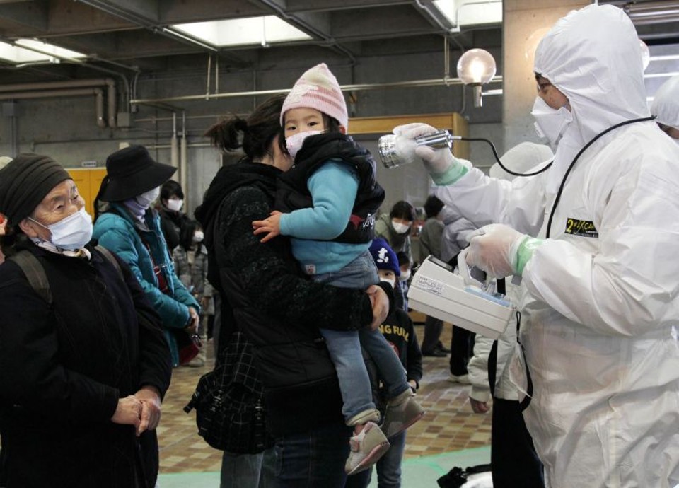Com roupa de proteção, técnico usa contador para verificar os níveis de radiação em vítimas do terremoto na cidade de Koriyama, na província de Fukushima, uma das mais afetadas pelo tremor e tsunami | Ken Shimizu/ AFP