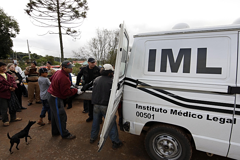 Com a ajuda de populares, funcionários do Instituto Médico-Legal de Curitiba carregam um cadáver na única viatura que ainda funciona: estrutura deficitária e falta de pessoal prejudicam o trabalho | Albari Rosa/Gazeta do Povo