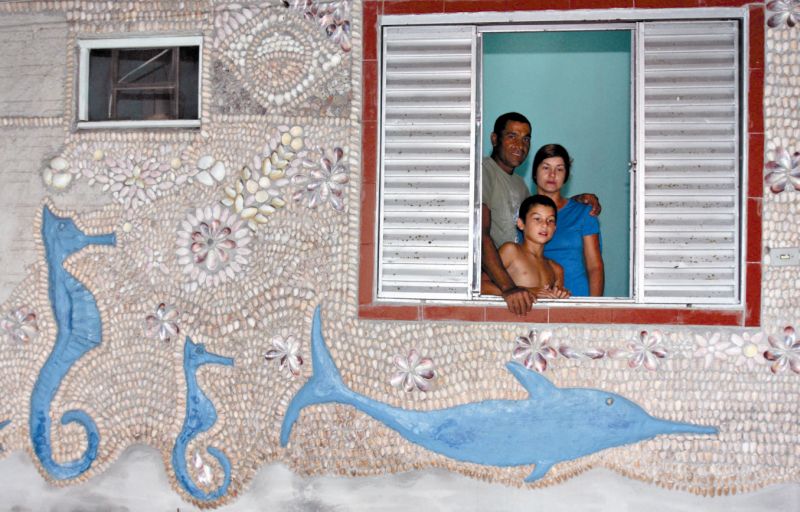 O pescador Marcos Antônio Paiva da Silva e sua família diante do mar de conchas em sua parede | Walter Alves/Gazeta do Povo