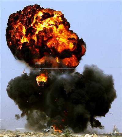 Veículo de rebeldes líbios é atingido por uma bomba lançada por soldados leais ao líder Muamar Kadafi, entre Ras Lanuf e Bin Jiwad, na Líbia | REUTERS/Goran Tomasevic