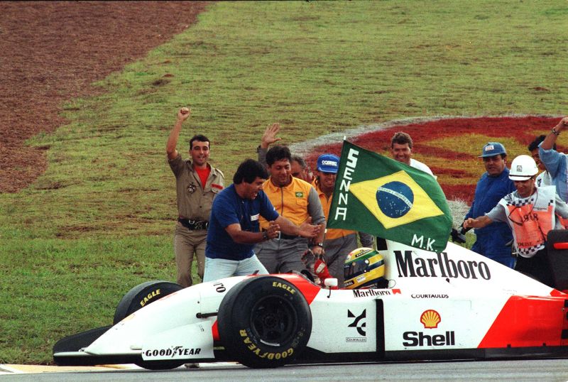 Torcida brasileira invade a pista e entrega uma bandeira estilizada para Ayrton Sena comemorar a vitória em Interlagos | Edu Garcia/ AE