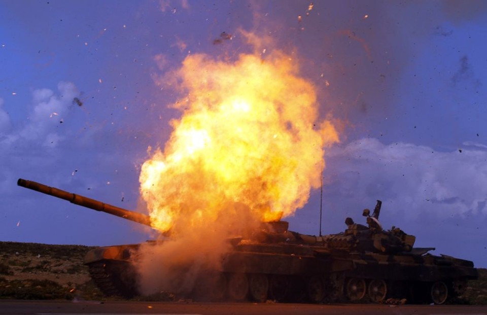 Um tanque pertencente às forças do ditador Muamar Kadafi explode depois de um ataque aéreo da coalizão, numa estrada entre Benghazi e Ajdabiyah | Goran Tomasevic/Reuters