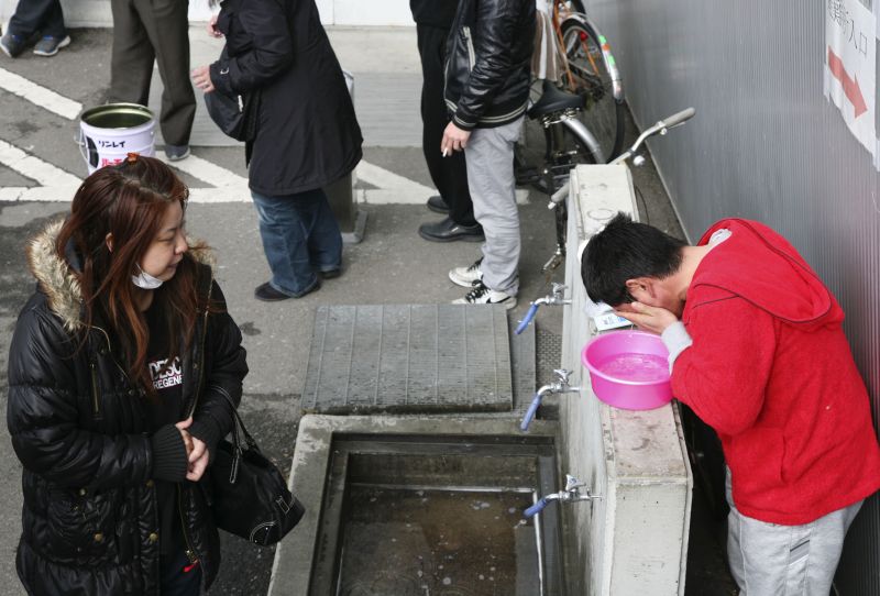 Trabalhador evacuado utiliza água da torneira para lavar o rosto em uma das torneiras públicas em abrigo na cidade de Koriyama, 60km a oeste de Fukushima | AFP