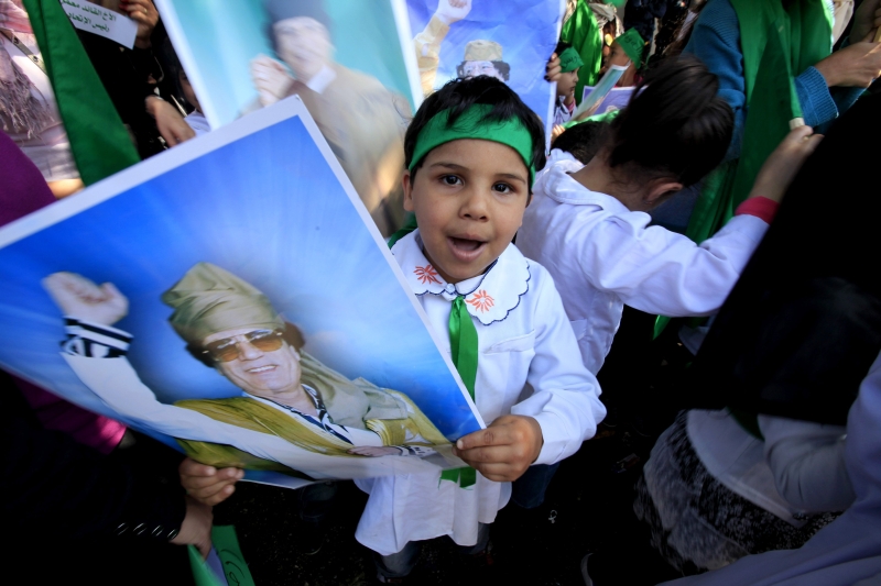 Estudante de escola primária segura cartaz do ditador Kadafi durante protesto contra a ofensiva da Otan no país | Zohra Benzemra/Reuters