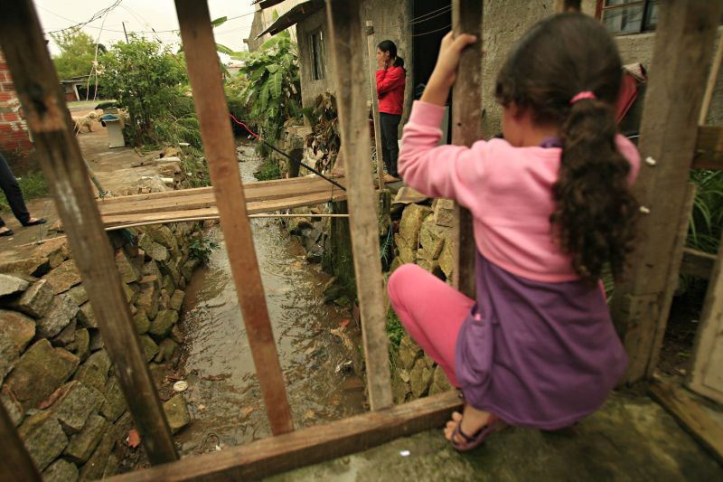 Júlia Gonçalves, neta de Marilene Gonçalves, 52 anos, observa córrego que transbordou: investimento para conter as águas feito pela avó não adiantou | Priscila Forone/Gazeta do Povo