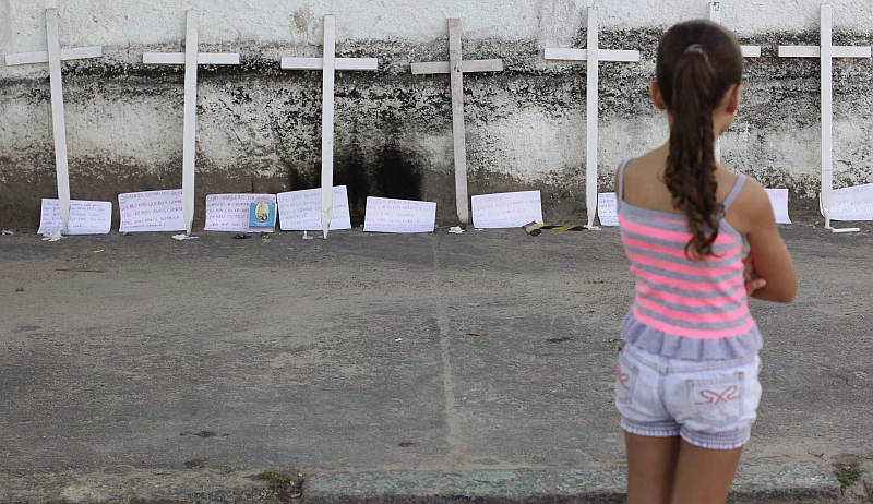 Criança observa cruzes deixadas em frente ao palco do massacre: psicólogos recomendam dizer sempre a verdade | Ricardo Moraes/Reuters