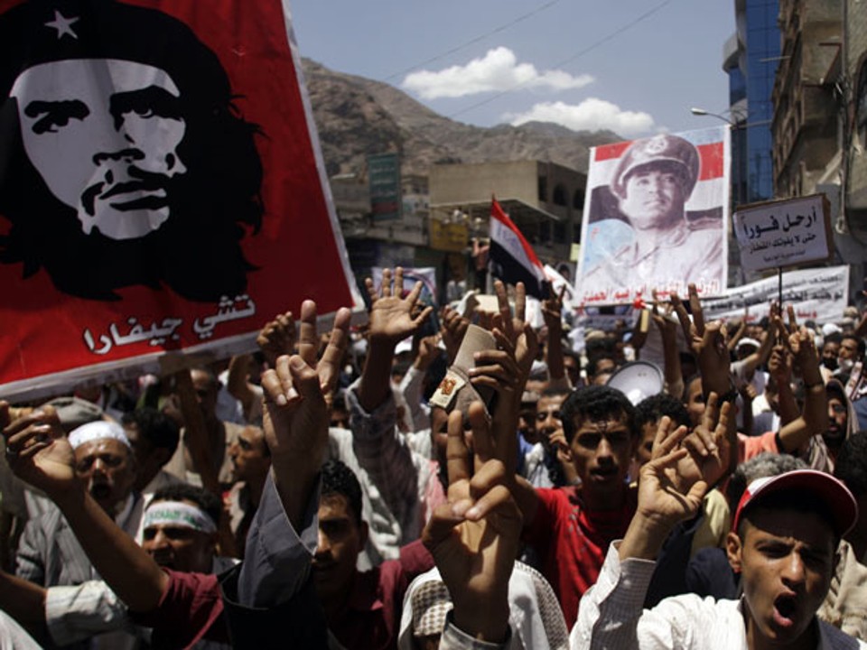 Manifestantes carregam posteres do líder revolucionário Che Guevara e do ex-presidente do Iêmen do Norte, Ibrahim al-Hamdi, durante protesto em Taiz, no sul do país | Foto: Khaled Abdullah / Reuters