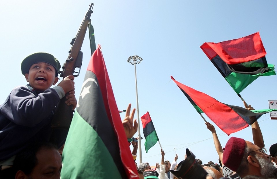 Garoto líbio exibe fuzil da Segunda Guerra junto à rebeldes anti-Kadafi, em Benghazi | AFP