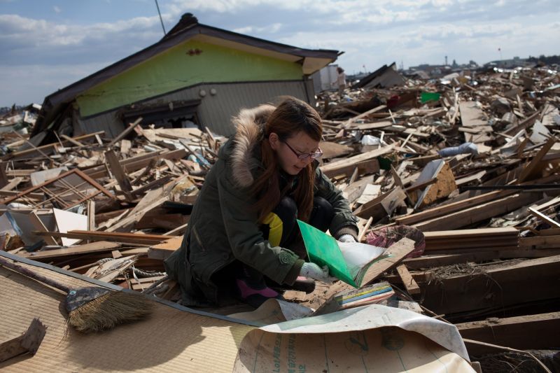 Sobrevivente do tsunami recupera álbum de fotos entre os destroços de sua casa, em Igashimatsushima, na província de Miyagi | Yasuyoshi Chiba/AFP