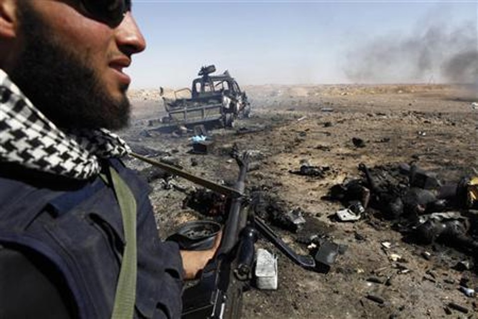 Rebelde líbio é visto perto do que ele diz ser corpos de membros de forças pró-Kadafi mortos por um ataque aéreo da OTAN, em Ajdabiyah | Reuters