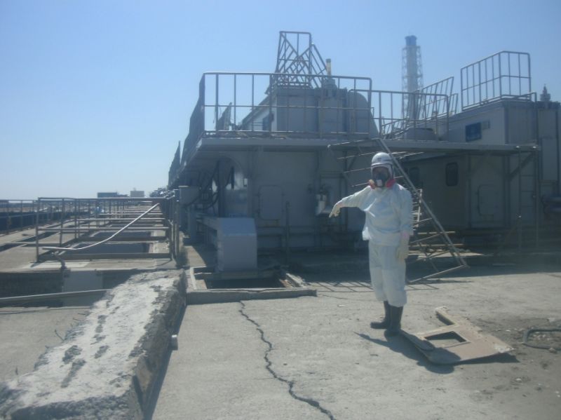 Trablhador veste roupa especial em frente a uma rachadura no concreto próxima ao reator n.º2 da usina de Fukushima | Reuters