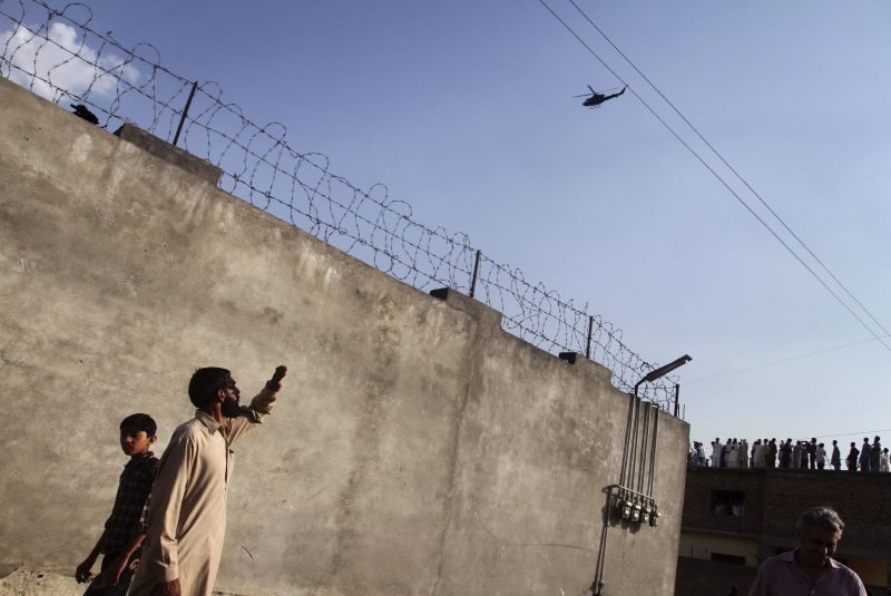 Moradores olham para helicóptero sobrevoando o complexo em Abbottabad, no Paquistão, que abrigava o líder da Al-Qaeda, Osama bin Laden, morto há uma semana por militares dos Estados Unidos | Faisal Mahmood/Reuters