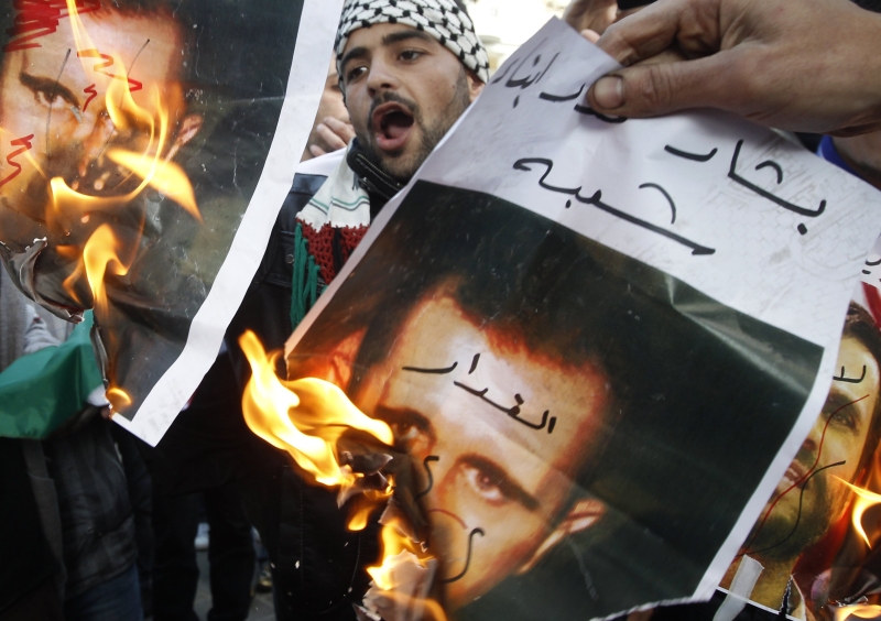 Manifestantes queimam cartazes com foto do presidente Bashar Assad, em Atenas, na Grécia | John Kolesidis/Reuters