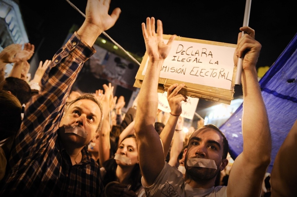 Pessoas tapam as bocas durante protesto contra a crise econômica espanhola, em Puerta del Sol | AFP