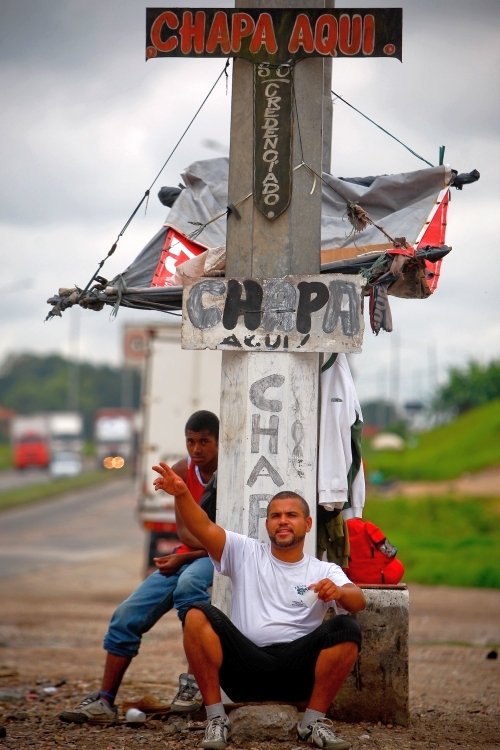 Sentado à beira da BR-476, em Curitiba, o chapa Odair da Silva pede trabalho. Leva até 150 quilos na cabeça | Daniel Castellano/Gazeta do Povo