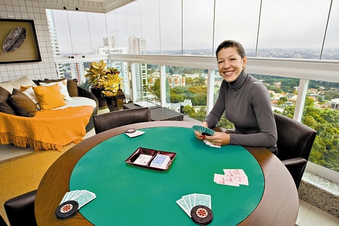 A mesa para jogar cartas com amigos e a chaise em fibra sintética oferecem diversão e relaxamento a Patrícia, o marido e convidados |