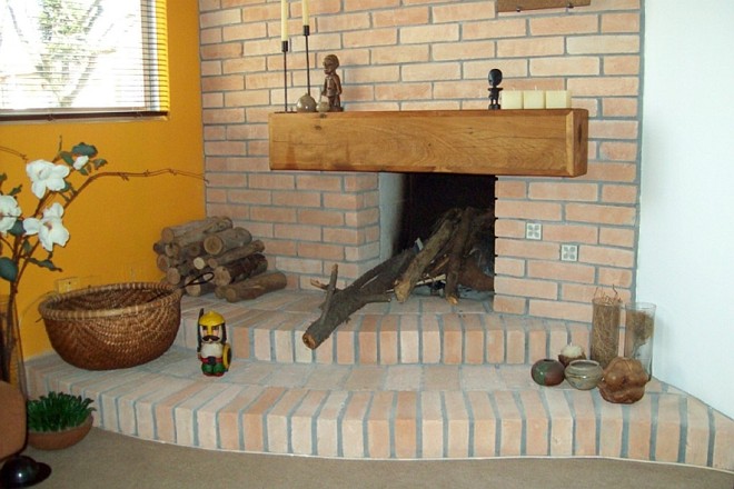 Tijolos à vista e um detalhe com madeira de demolição no projeto de lareira da arquiteta Rossana Masino |