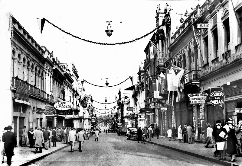 Dia da Vitória, 8 de maio de 1945, com a Rua XV de Novembro engalanada com adornos no Senadinho. A sacada da Gazeta do Povo aparece ornamentada com bandeiras dos países aliados |