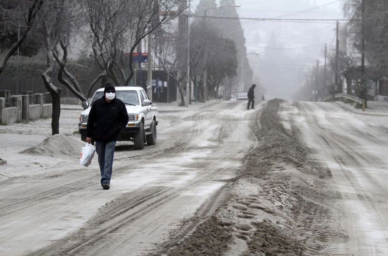 Morador de Bariloche usa máscara para caminhar por rua da cidade coberta de cinzas do complexo vulcânico Puyehue-Cordón Caulle, em erupção no sul do Chile | Chiwi Giambirtone/Reuters