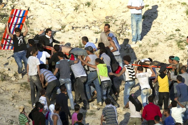 Manifestantes sírios carregam dois companheiros feridos pelas forças israelenses quando tentaram atravessar o arame farpado para entrar na região das Colinas de Golã | Jack Guez/AFP