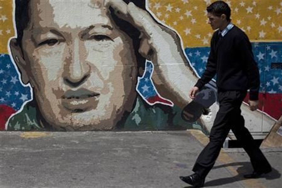 Pedestre passa em frente a um grafite com a imagem do presidente da Venezuela, Hugo Chávez, em Caracas | Reuters