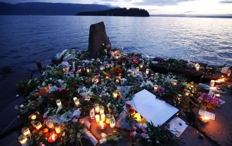 Flores e velas são vistas em um local temporário do memorial para as vítimas do tiroteio e ataque a bomba na Noruega, na costa em frente à ilha Utoeya, a noroeste de Oslo | Reuters