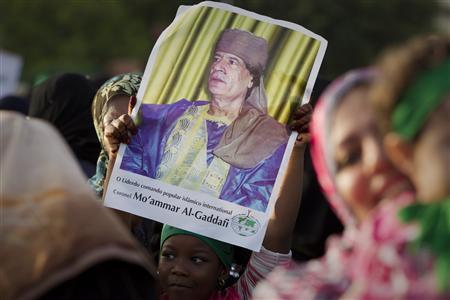 Garota segura cartaz com foto do líder líbio Muamar Kadafi durante manifestação pró-governo na cidade de Sirte | Reuters