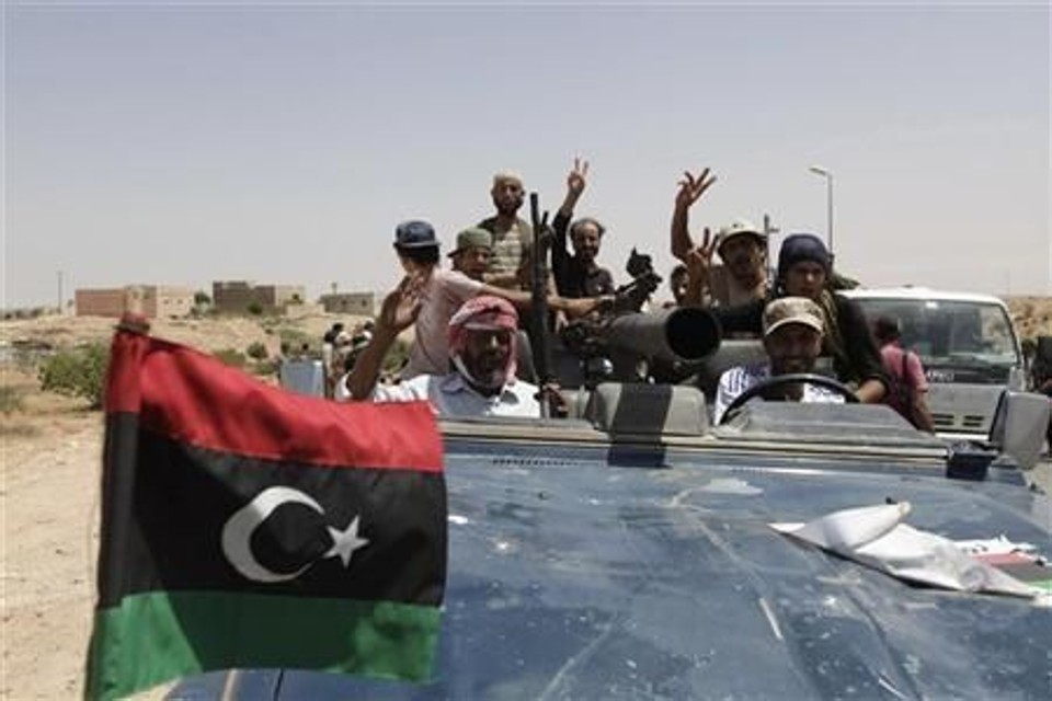 Rebeldes acenam na aldeia de Al-Qawalish, depois de assumirem a localidade, até então sob controle das tropas leais ao líder líbio Muamar Kadafi, na Líbia | Reuters