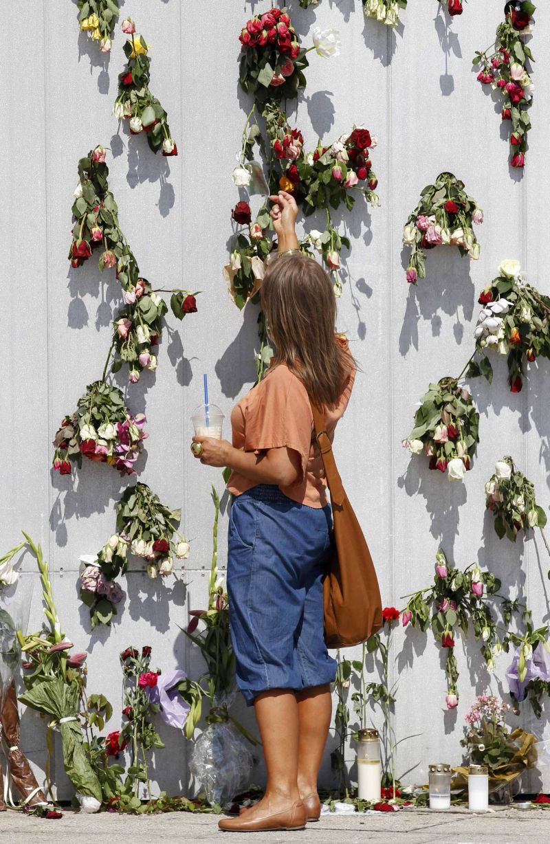 Mulher coloca flores em mural para homenagear as vítimas dos ataques de sexta-feira, na Noruega | Cathal McNaughton/Reuters
