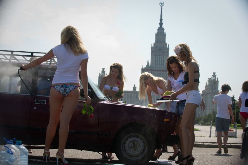 Mulheres de biquíni lavam carros gratuitamente na Universidade Estatal de Moscou, fazendo campanha por Putin | AFP