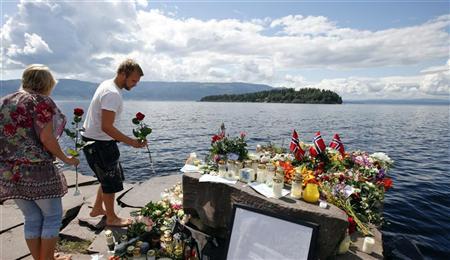 Pessoas deixam homenagens na costa em frente à ilha de Utoeya, ao noroeste de Oslo, onde 68 pessoas morreram no massacre a tiros | Reuters