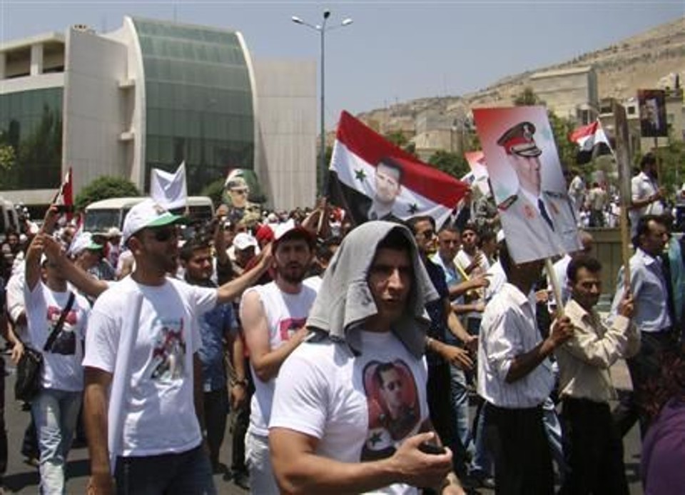 Partidários do governo sírio mostram cartazes do presidente Assad a caminho da embaixada francesa em Damasco para protestar | Reuters