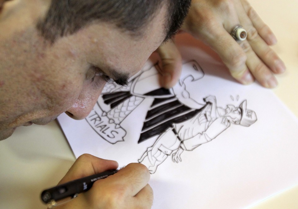 O cartunista Carlos Latuff finaliza uma de suas charges | REUTERS/Sergio Moraes