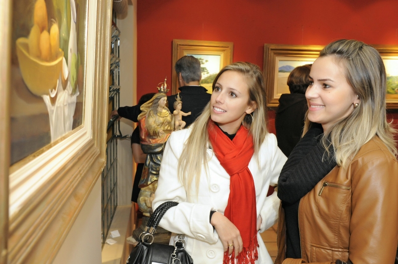 As arquitetas Lisiê Tavares e Cristhiani Versan conferem uma das obras da exposição individual de Coriolano Silveira da Mota inaugurada nesta terça-feira, com movimentado coquetel, na galeria do artista plástico Celso Coppio | Gerson Lima