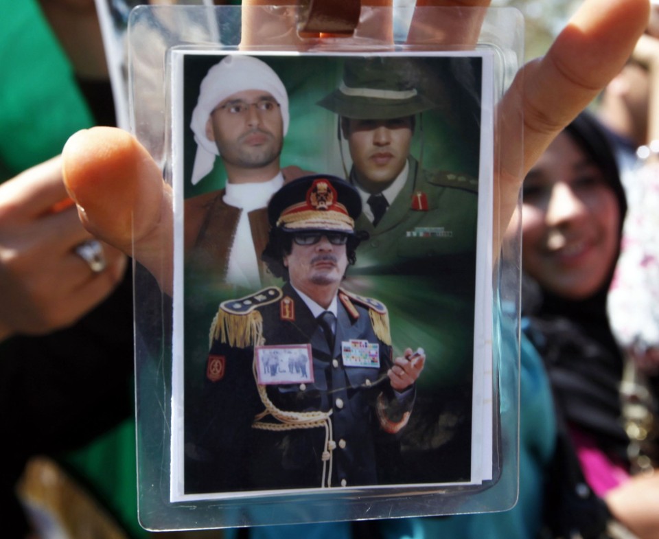 Khamis Kadafi é visto ao lado direito do seu pai, Muamar, e do seu irmão Saif al-Islamem em foto exibida por estudante líbio | REUTERS/Ahmed Jadallah/Files