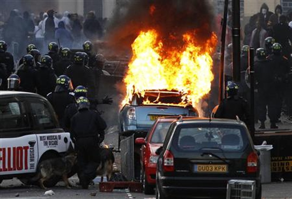 Policiais bloqueiam via perto de um carro incendiado numa rua em Hackney, em Londres, nesta segunda-feira | Reuters