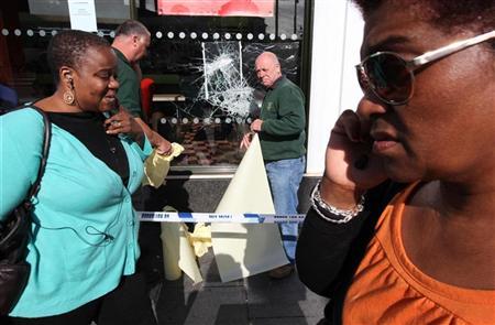 Pedestres caminham em frente a uma janela quebrada de um restaurante do Mc Donald s, depois de saques durante a noite em Brixton, em Londres | Reuters