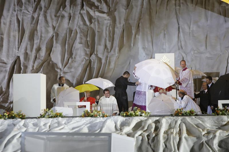 Vários sacerdotes se protegeram da chuva e do vento durante a vigília | EFE